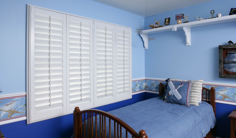 White plantation shutters in blue kids bedroom in New York City 